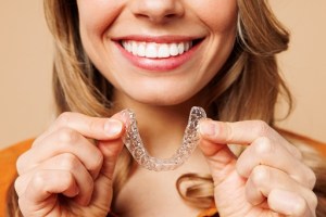 woman smiling and holding clear aligners