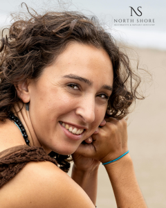 Woman sitting on beach smiling over her shoulder